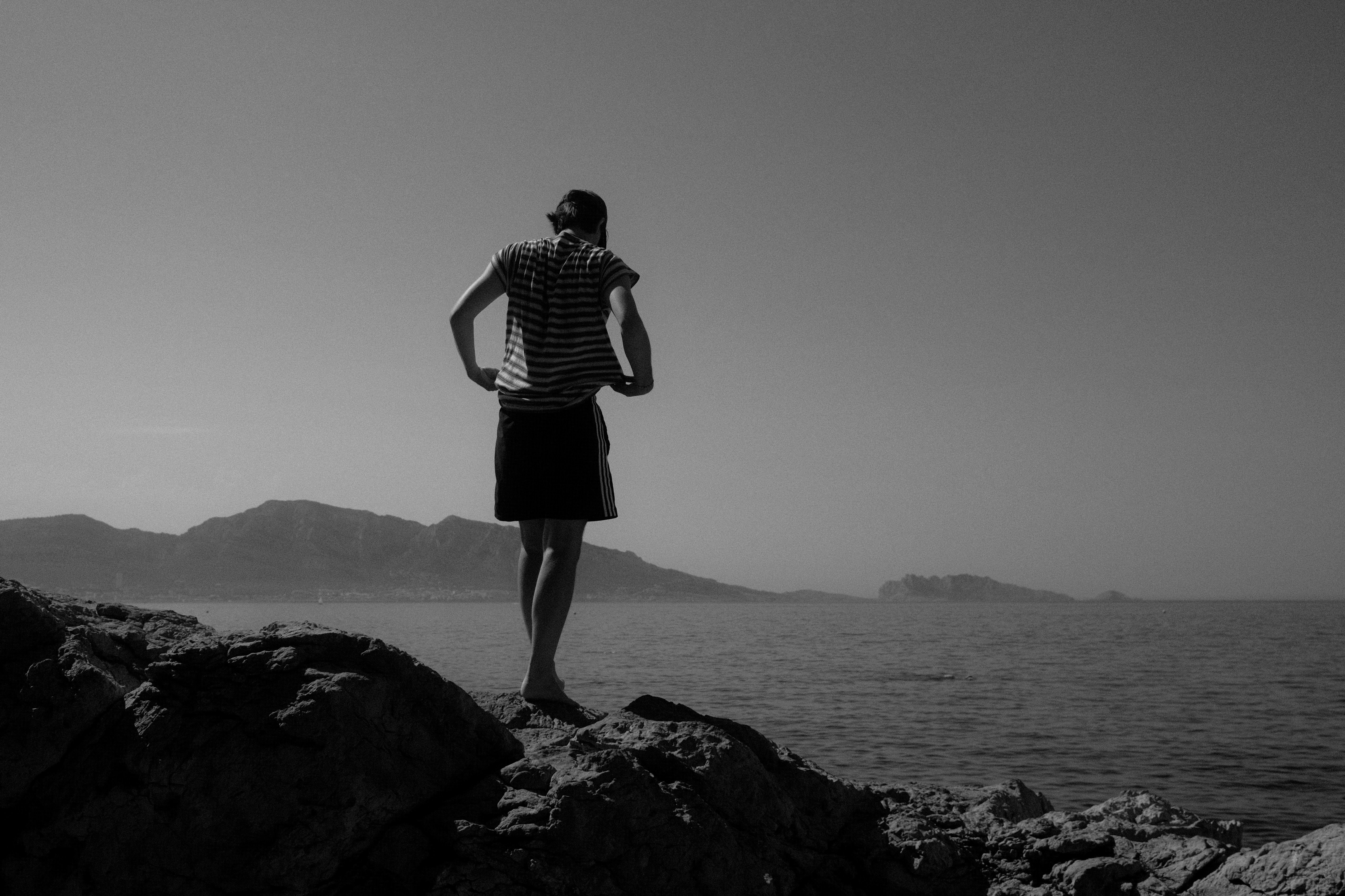 Christof standing barefoot on coastal rocks, looking out over the sea